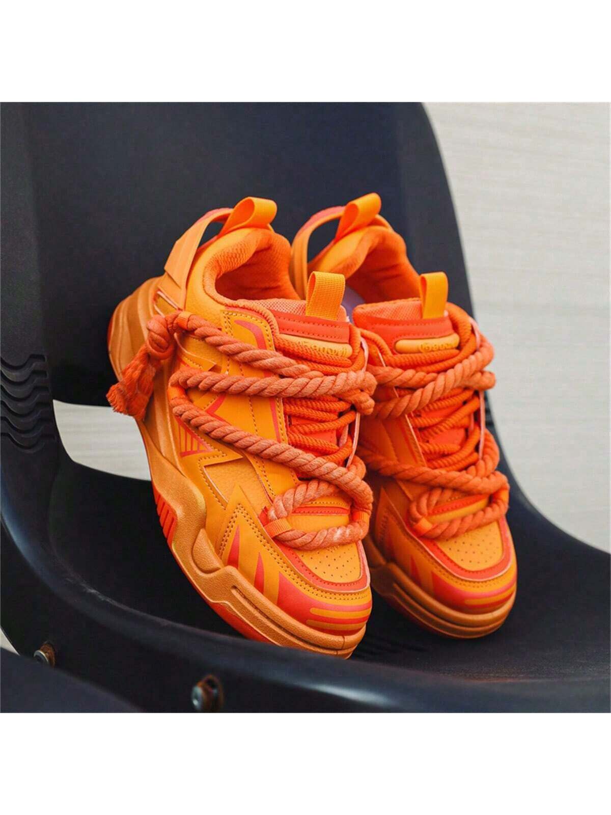 Chunky orange sneakers with thick rope laces, futuristic streetwear platform shoes