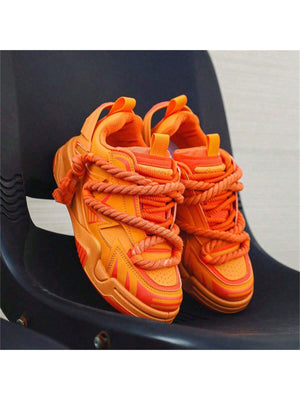 Chunky orange sneakers with thick rope laces, futuristic streetwear platform shoes