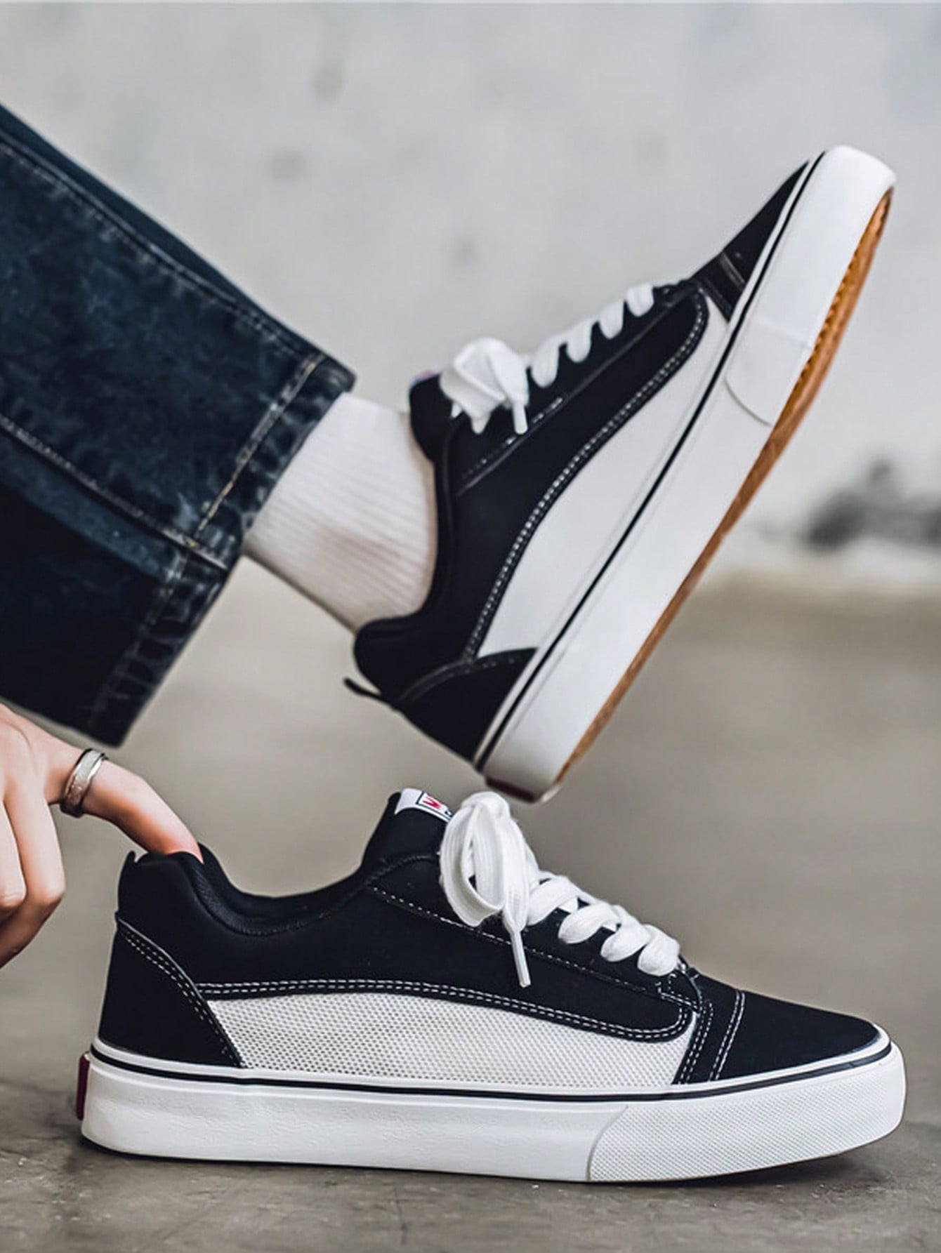 Black and white low-top sneakers with lace-up closure, mesh upper, and flat rubber outsole, modern streetwear shoes