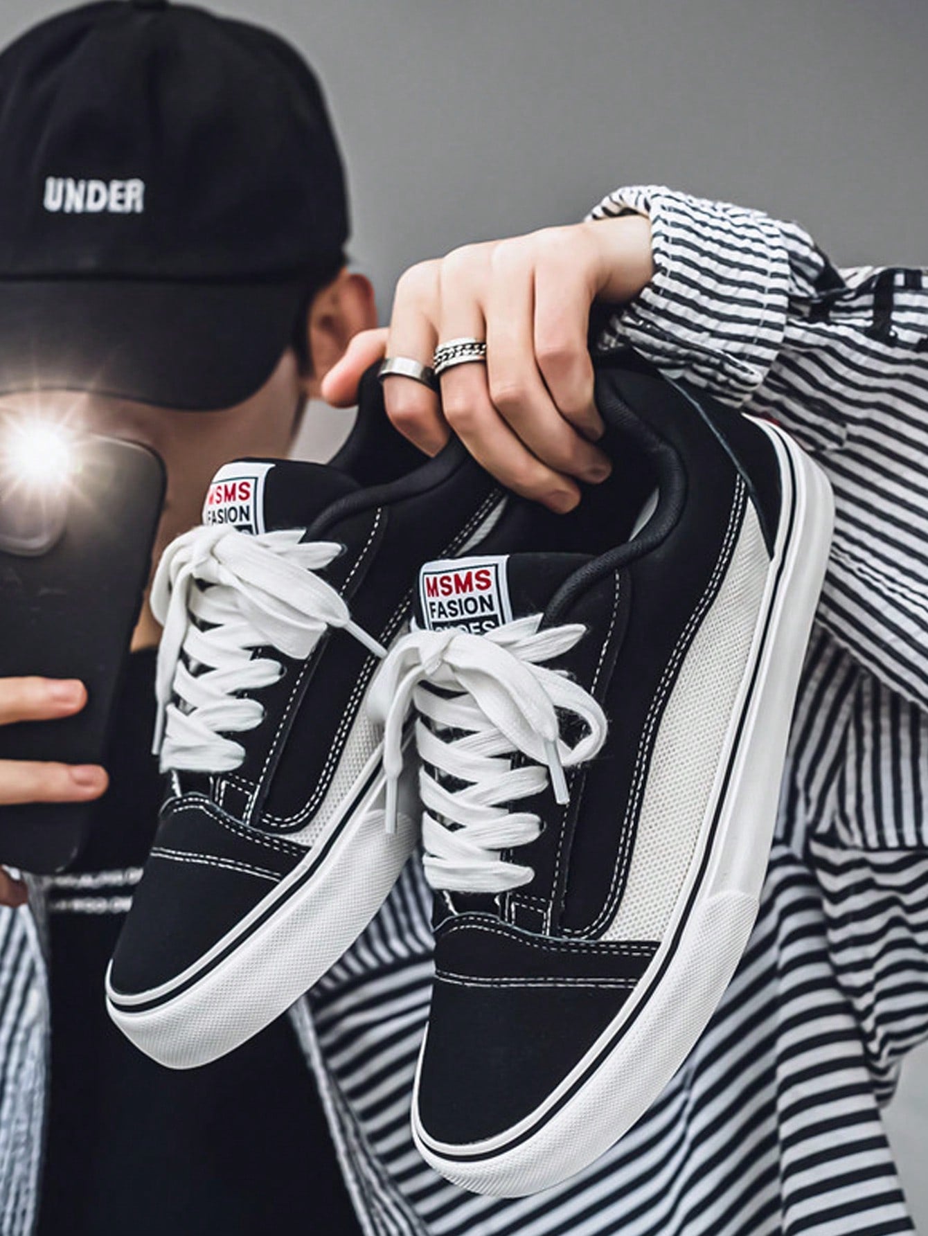 Black and white low-top sneakers with lace-up closure, mesh upper, and flat rubber outsole, modern streetwear shoes