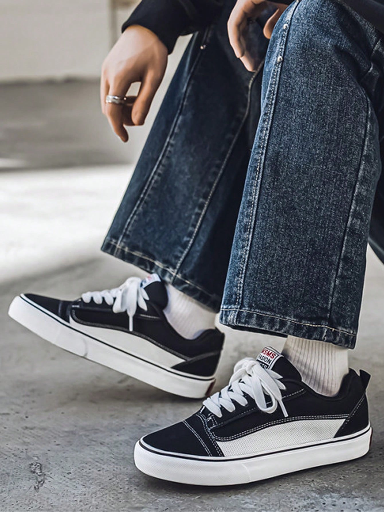 Black and white low-top sneakers with lace-up closure, mesh upper, and flat rubber outsole, modern streetwear shoes