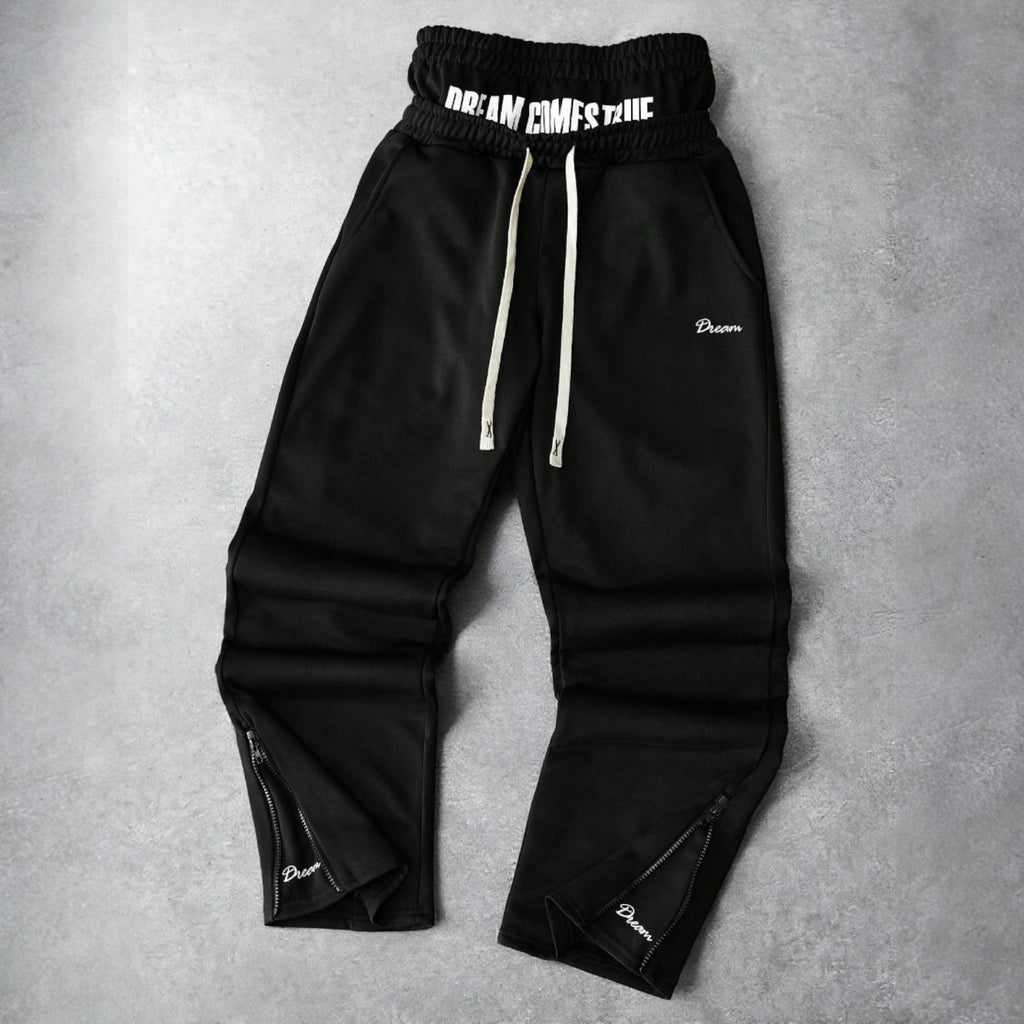 Black Japanese streetwear jogger pants with DREAM COMES TRUE patch, drawstring waist, and zippered ankles