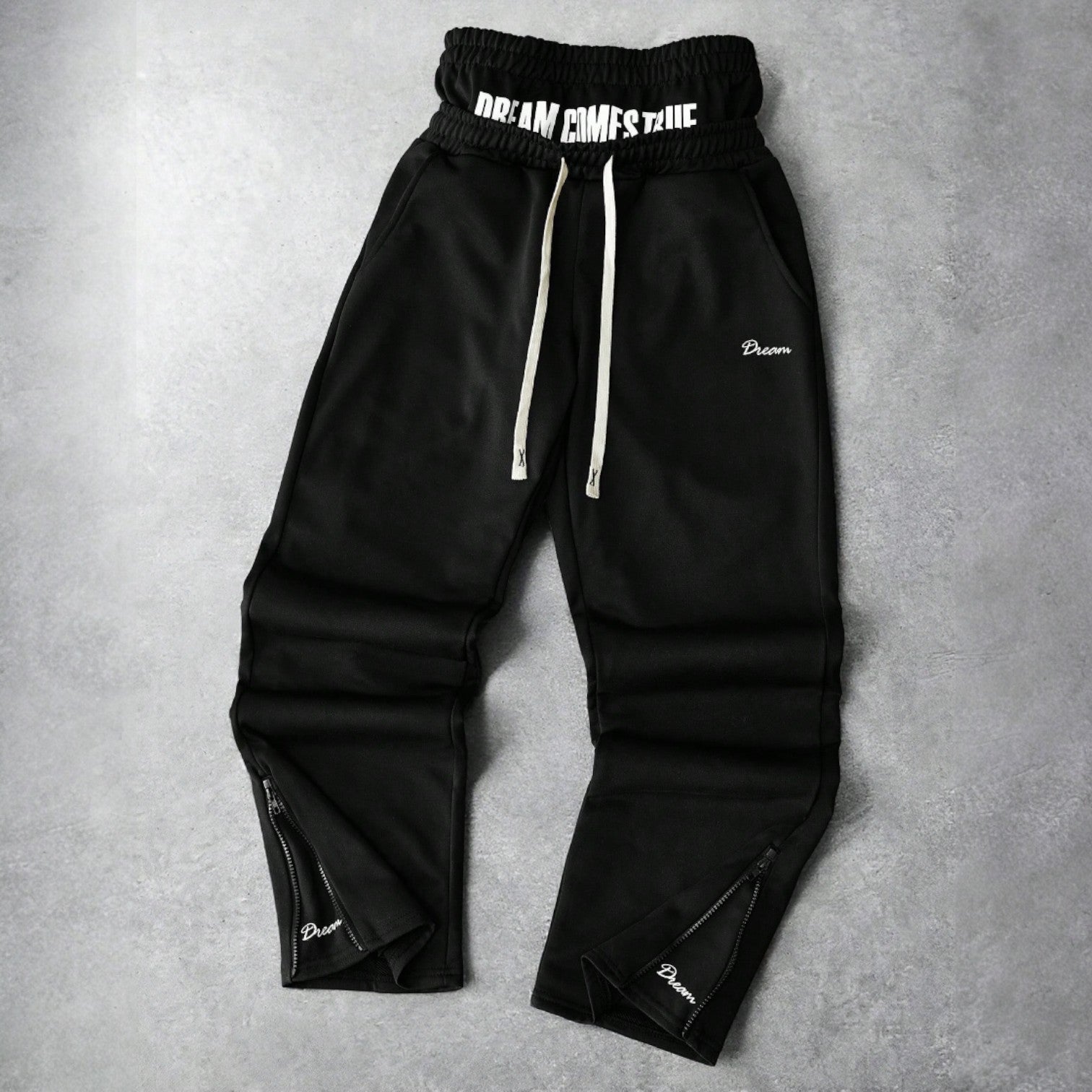 Black Japanese streetwear jogger pants with DREAM COMES TRUE patch, drawstring waist, and zippered ankles