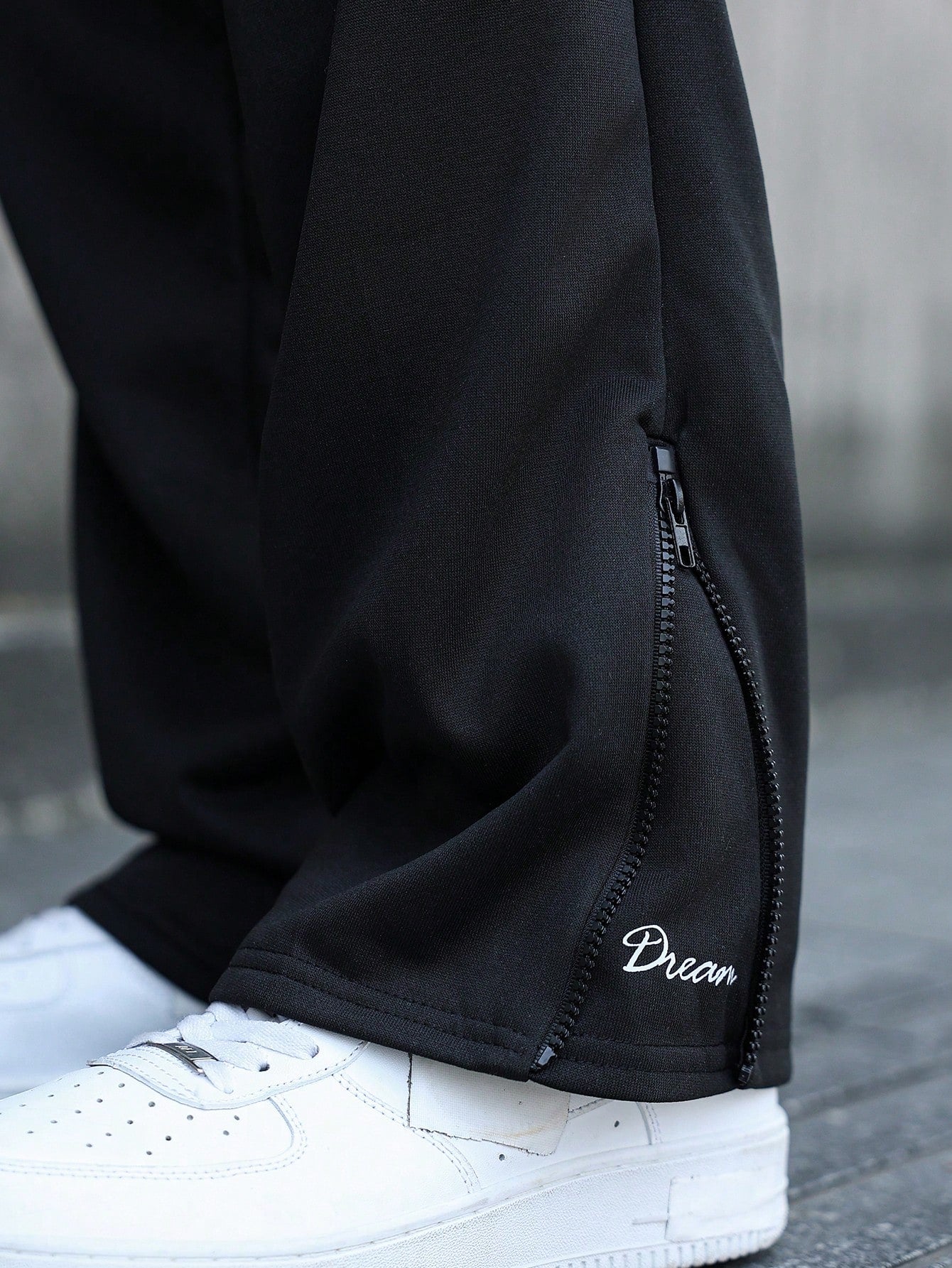 Black Japanese streetwear jogger pants with DREAM COMES TRUE patch, drawstring waist, and zippered ankles