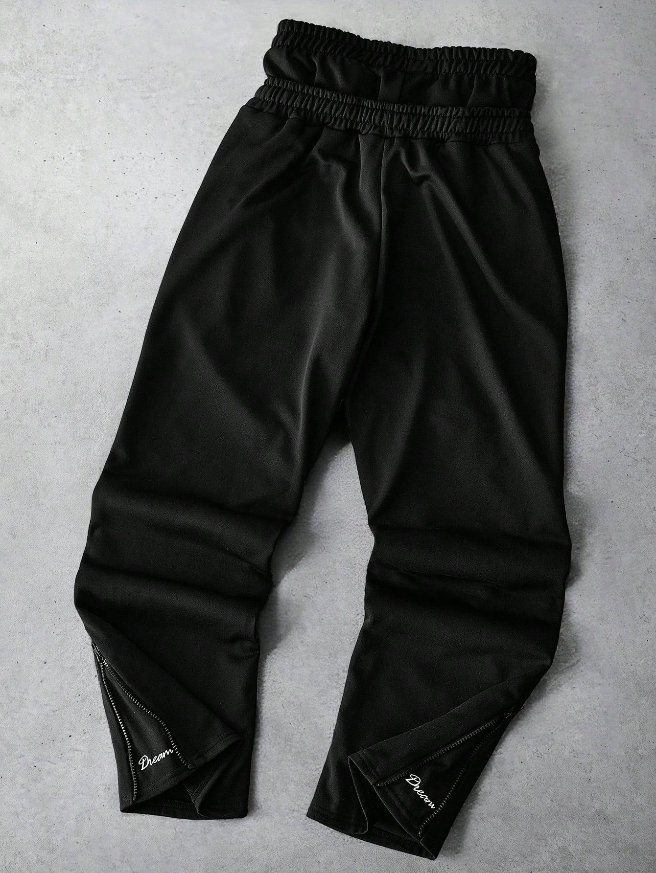Black Japanese streetwear jogger pants with DREAM COMES TRUE patch, drawstring waist, and zippered ankles